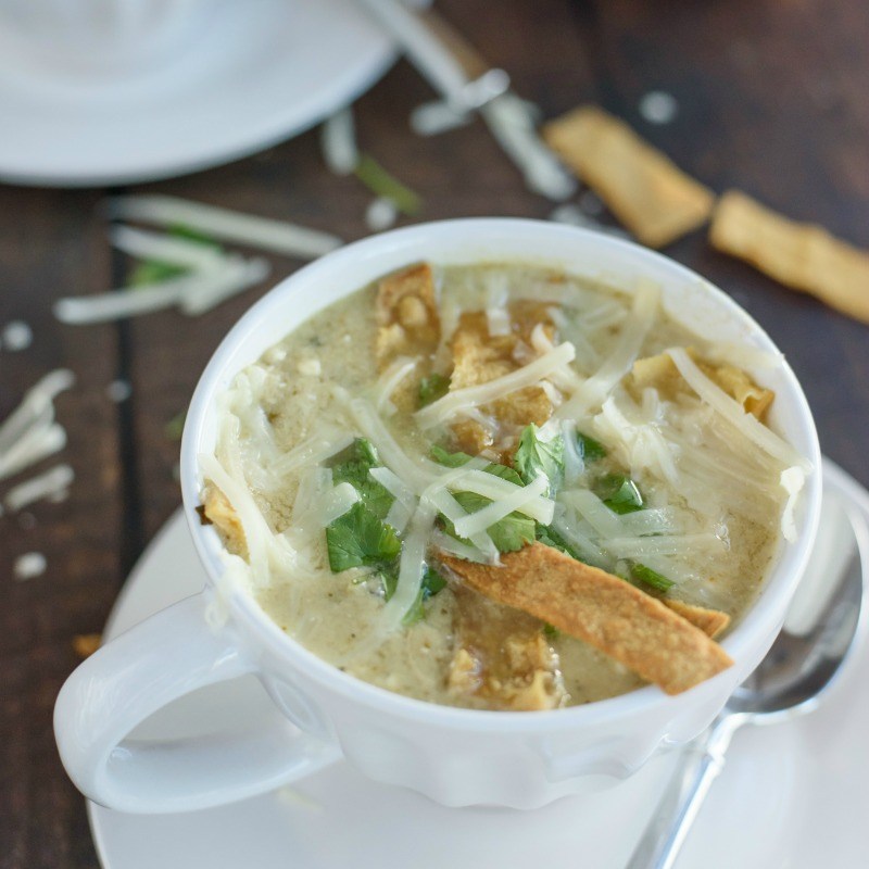 Slow cooker chicken enchilada soup in a mug with melted cheese and crunchy tortilla strips